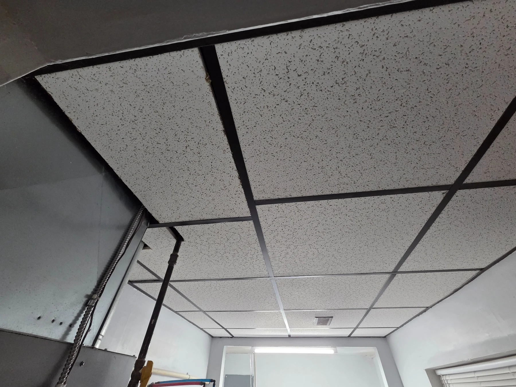 Completed suspended ceiling installed around existing mechanical and electrical infrastructure.