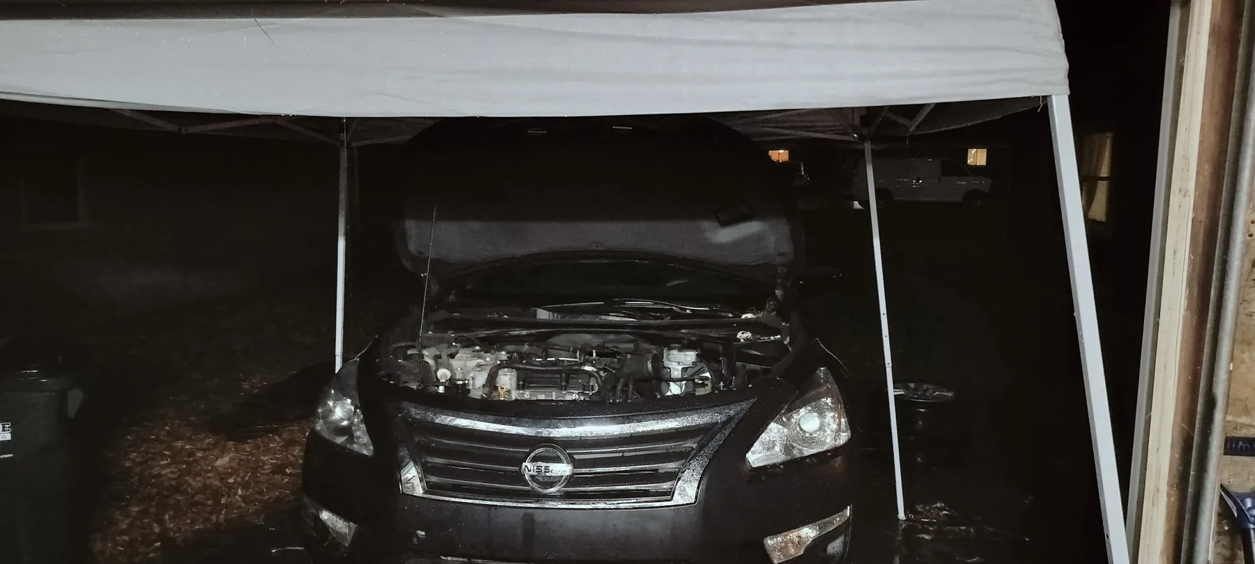 Nissan sedan staged outdoors during major engine and drivetrain work.